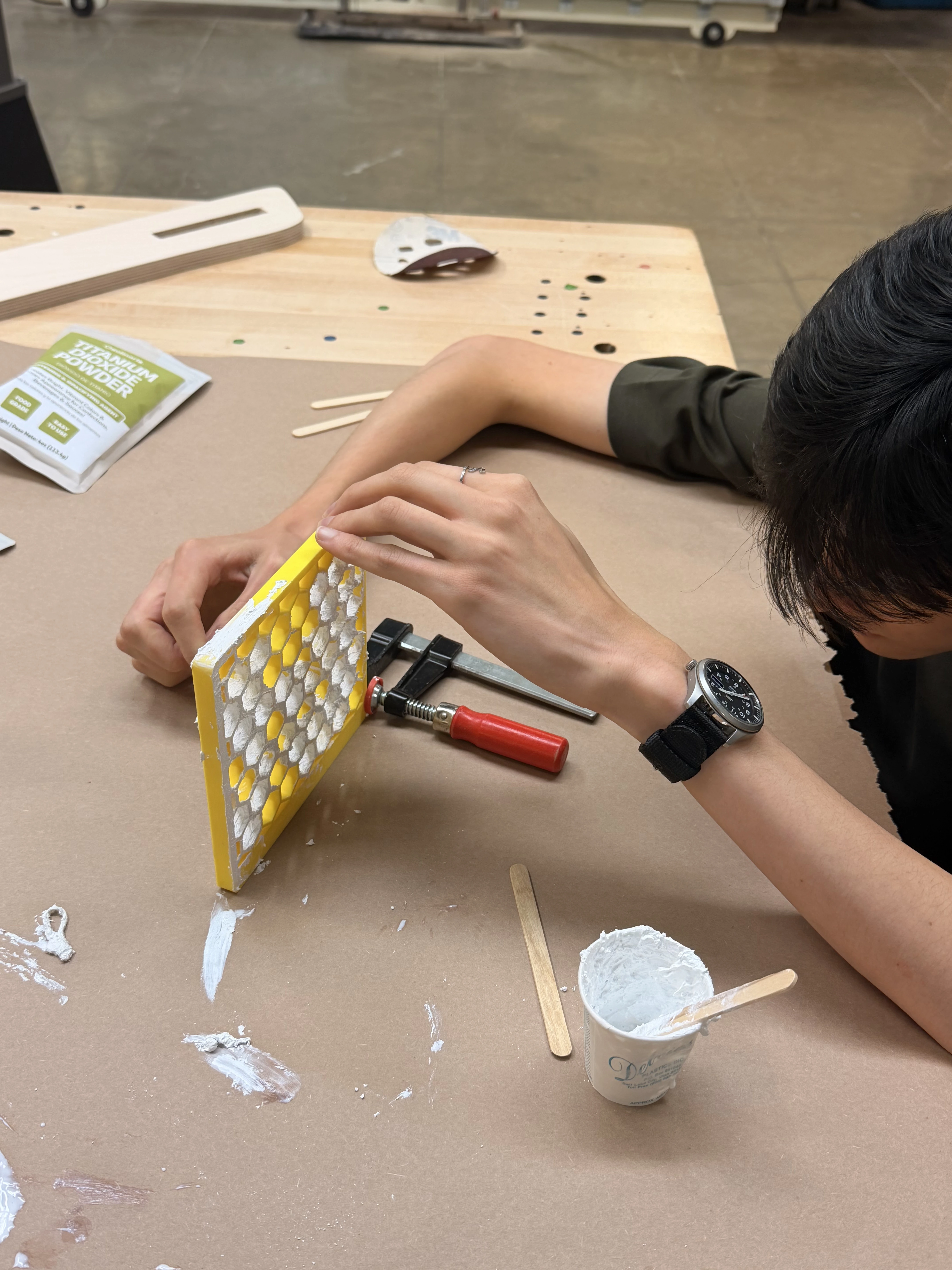 Clamping a yellow hexagonal lattice panel while coating it with white photocatalytic paste